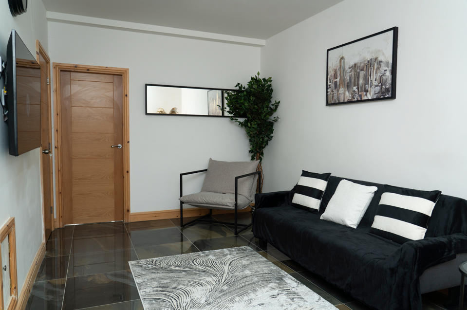 Elegant living space with dark sofa, grey armchair, contemporary artwork, and wooden finishes